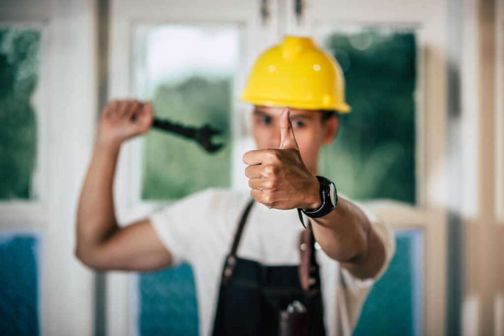 a technician holding a screwdriver with a thumbs up - garage door repair in grimsby